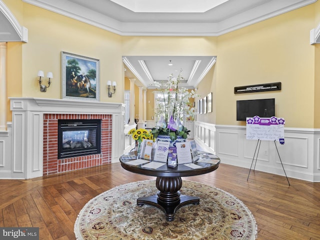 interior space with a fireplace, a raised ceiling, ornamental molding, and wood-type flooring