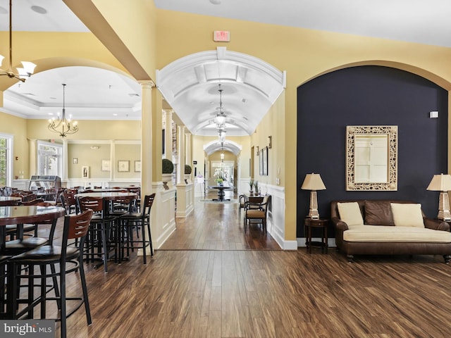 entryway with lofted ceiling, decorative columns, dark hardwood / wood-style floors, and a notable chandelier