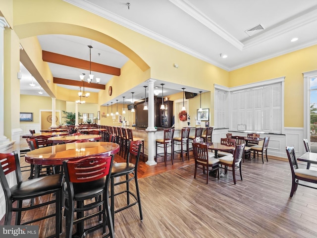 dining space featuring decorative columns, crown molding, hardwood / wood-style flooring, and a notable chandelier