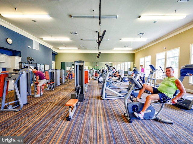 exercise room featuring ornamental molding and dark colored carpet