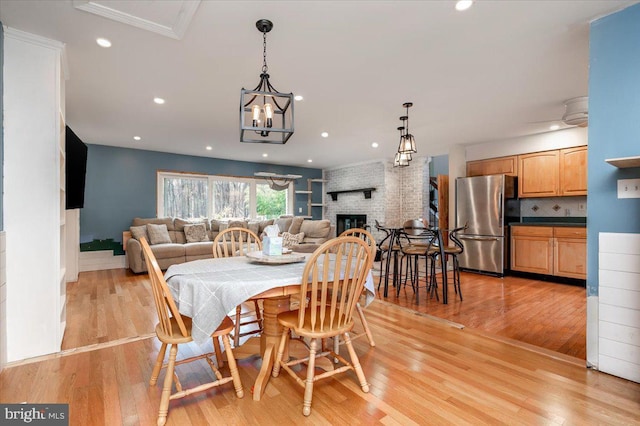 dining area featuring a brick fireplace and light wood-type flooring