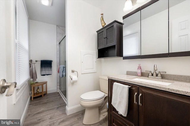 bathroom with vanity, toilet, a shower with shower door, and hardwood / wood-style floors