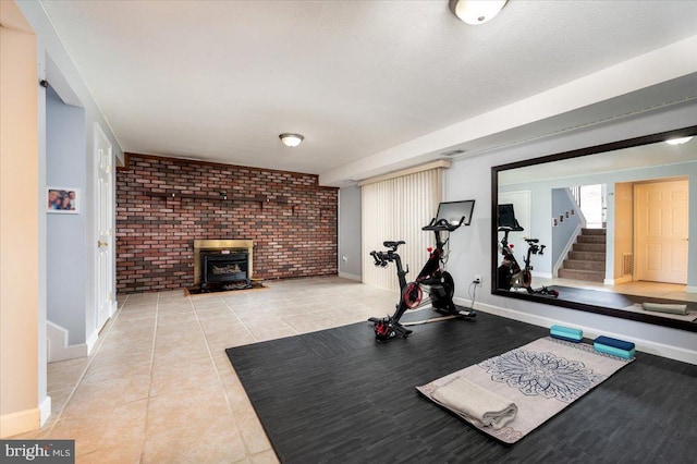 exercise room featuring brick wall, a wood stove, and light tile patterned floors