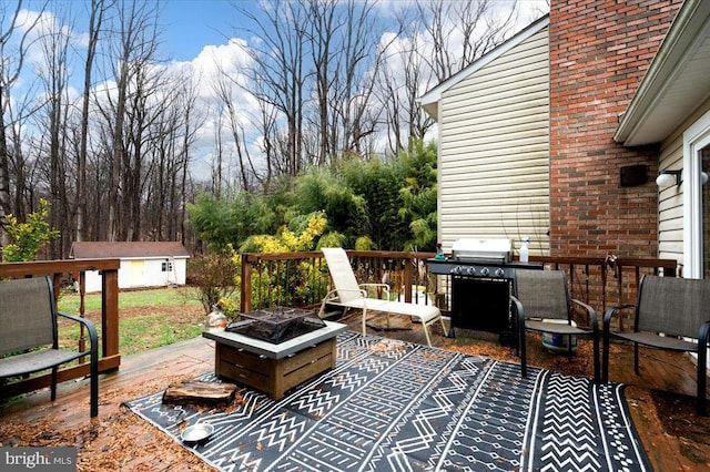 view of patio / terrace featuring a grill, a deck, a storage unit, and an outdoor fire pit