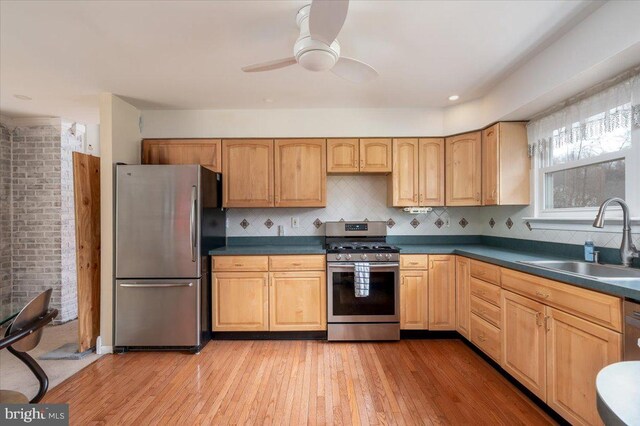 kitchen with tasteful backsplash, sink, stainless steel appliances, and light wood-type flooring