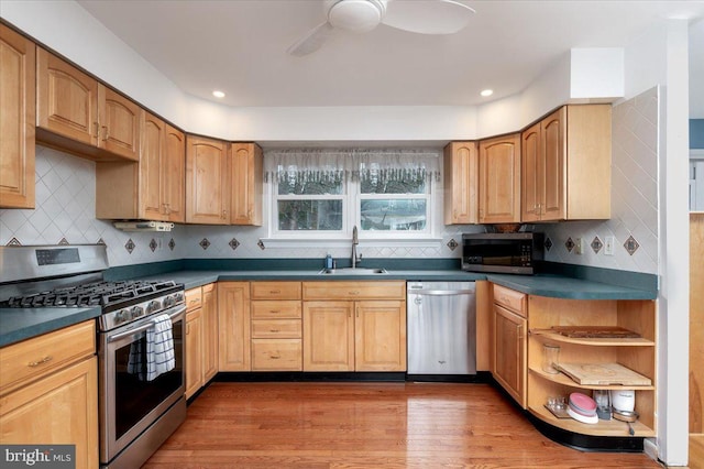 kitchen with sink, ceiling fan, stainless steel appliances, tasteful backsplash, and wood-type flooring