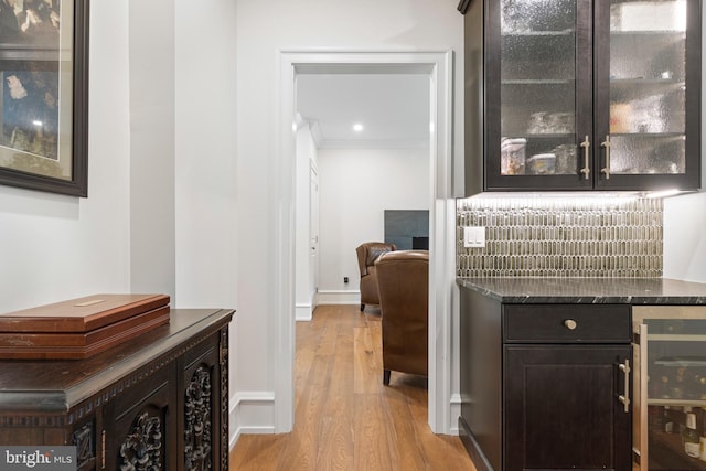 bar featuring light wood-type flooring, crown molding, and wine cooler