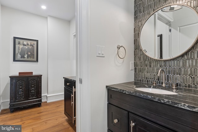 bathroom featuring wood-type flooring, tasteful backsplash, and vanity