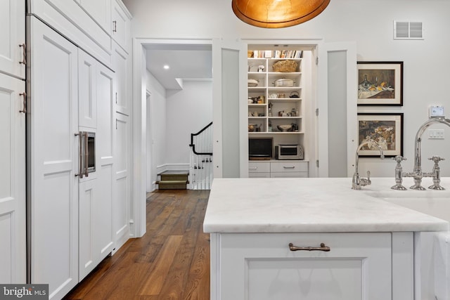 interior space featuring dark wood-type flooring, light stone countertops, and white cabinetry