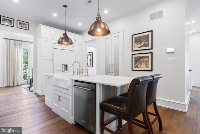 kitchen with dark hardwood / wood-style floors, pendant lighting, an island with sink, a kitchen bar, and white cabinets