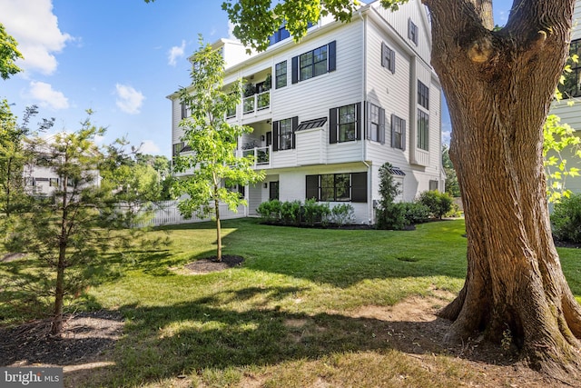 view of front of house featuring a balcony and a front lawn