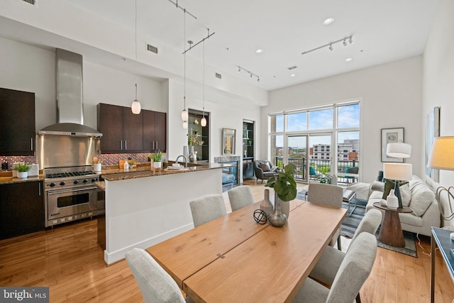 dining room featuring a high ceiling, rail lighting, and light hardwood / wood-style floors