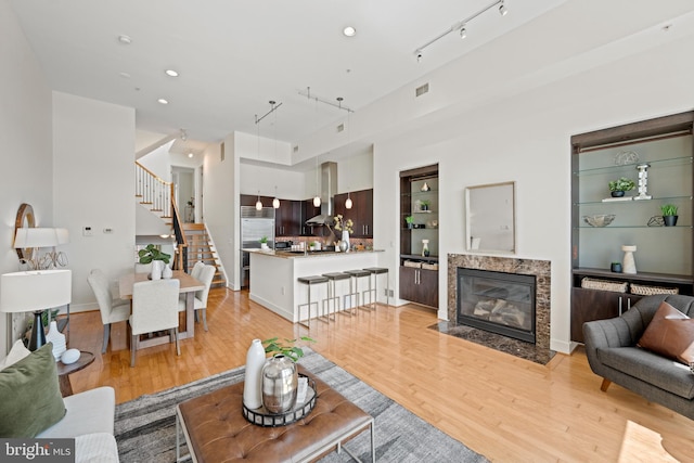 living room featuring rail lighting, a premium fireplace, and light wood-type flooring