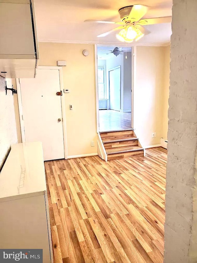 spare room with crown molding, baseboard heating, ceiling fan, and light hardwood / wood-style floors