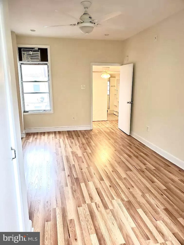 spare room with ceiling fan, a wall unit AC, and light wood-type flooring