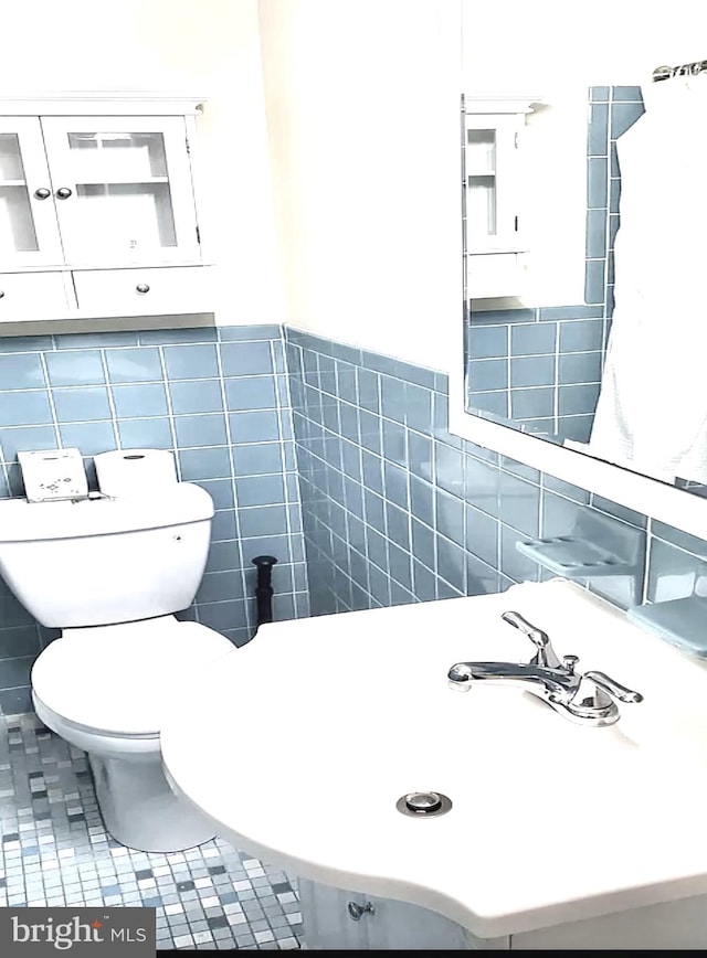 bathroom featuring backsplash, tile patterned flooring, tile walls, toilet, and sink