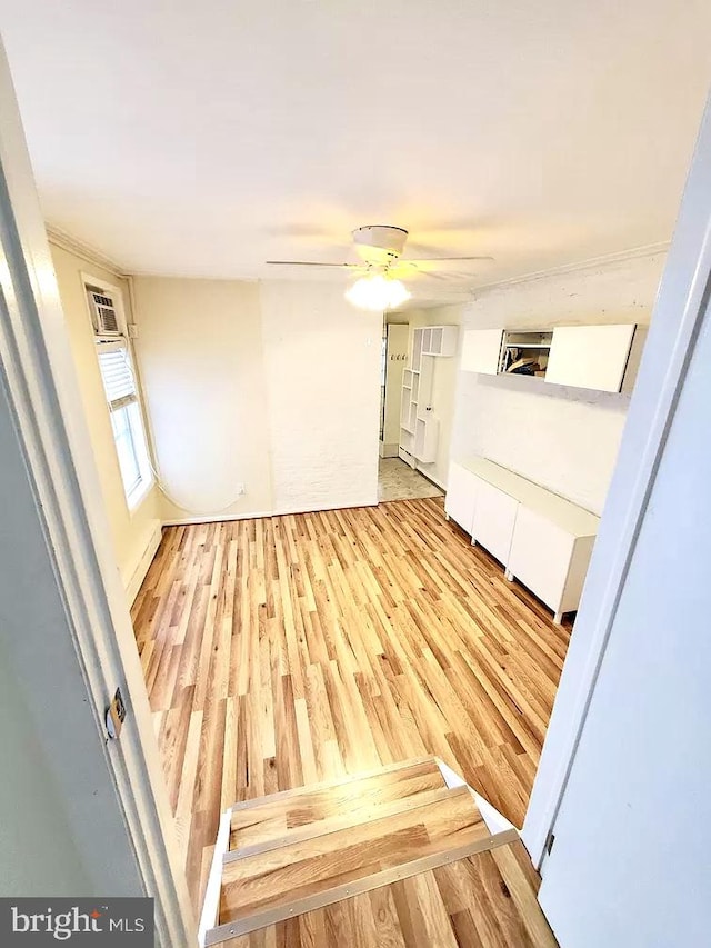 interior space featuring light wood-type flooring, a wall unit AC, and ceiling fan