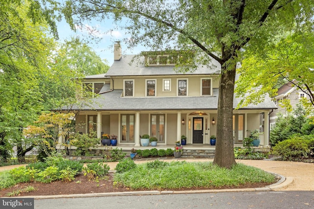 view of front of property with a porch, a chimney, and stucco siding