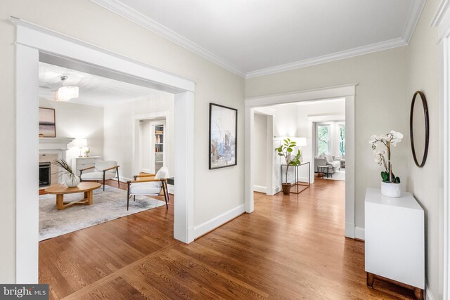 corridor featuring crown molding, baseboards, and wood finished floors