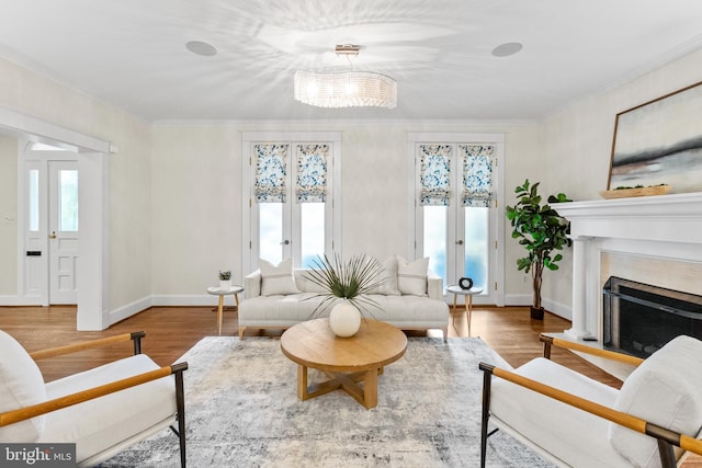 living room with plenty of natural light, ornamental molding, wood finished floors, and french doors