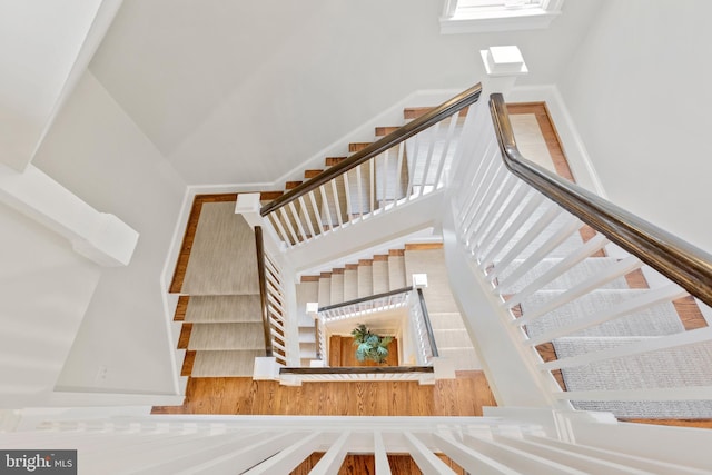 stairway with a towering ceiling and hardwood / wood-style flooring