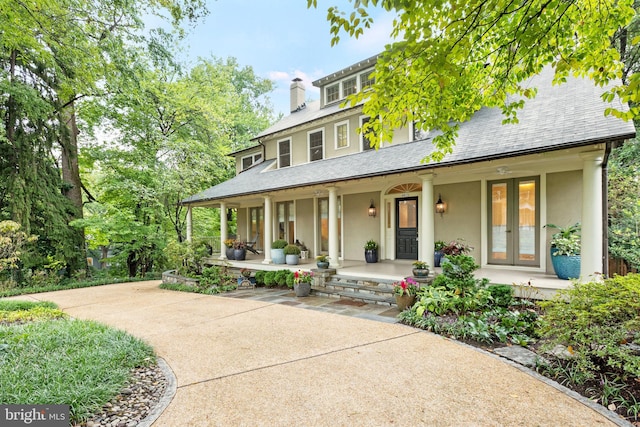 view of front of property with covered porch, a shingled roof, french doors, stucco siding, and a chimney