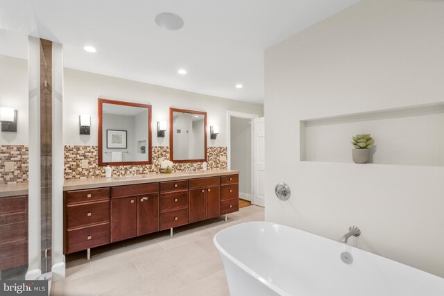 bathroom featuring double vanity, a freestanding tub, tasteful backsplash, and a sink