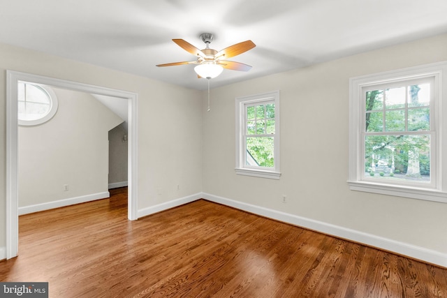 empty room with light wood finished floors, a ceiling fan, and baseboards