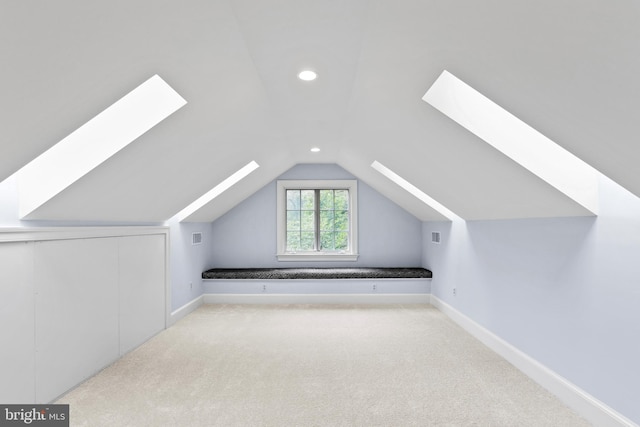 additional living space featuring vaulted ceiling with skylight and light carpet