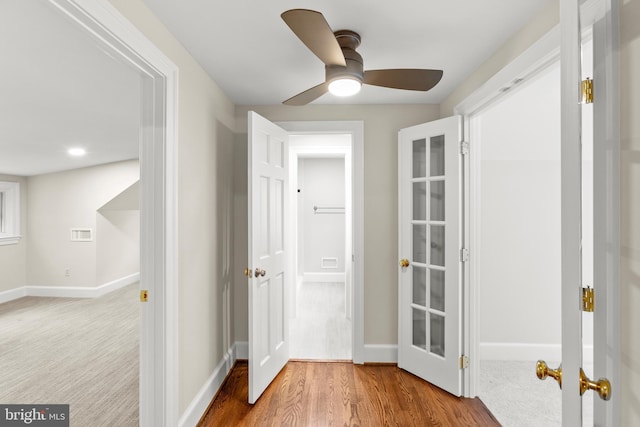 hall featuring baseboards, wood finished floors, and french doors