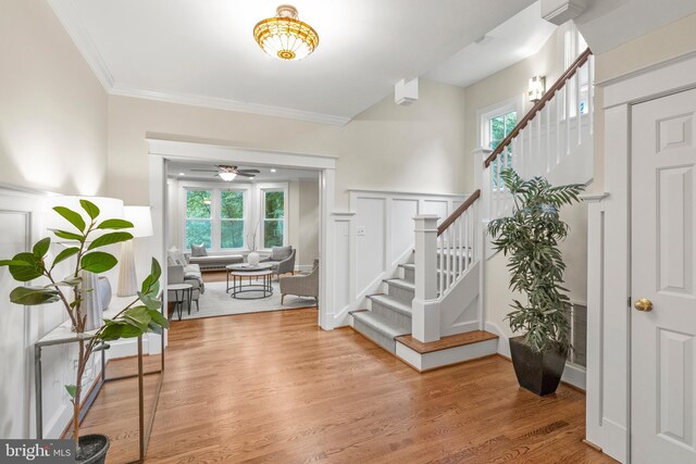 foyer featuring stairway, a healthy amount of sunlight, crown molding, and light wood-style flooring