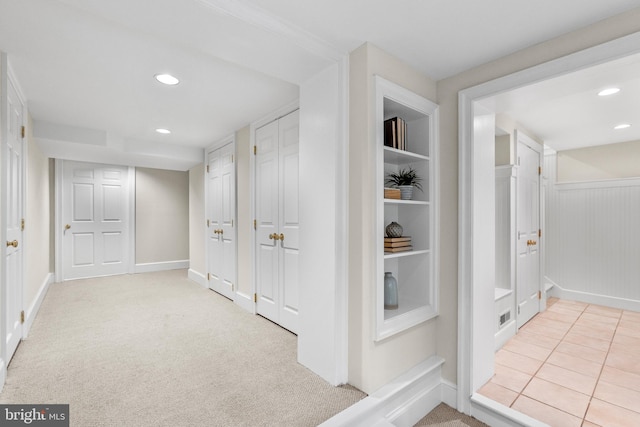 corridor with built in shelves and light colored carpet