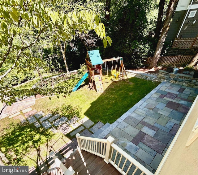 view of yard featuring a wooden deck, a patio area, and a playground