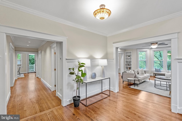 hall featuring light wood-style floors, baseboards, and ornamental molding