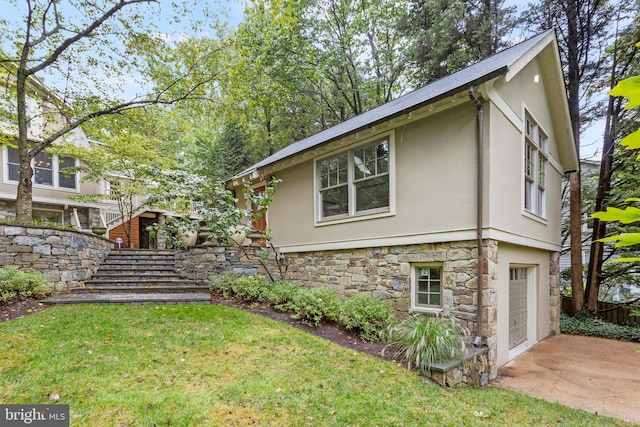 view of side of home featuring concrete driveway, stone siding, stairway, an attached garage, and stucco siding