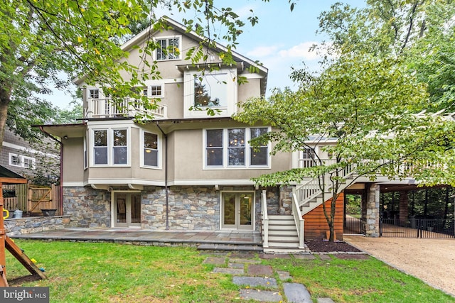 view of front of home featuring fence, stairs, stone siding, french doors, and stucco siding