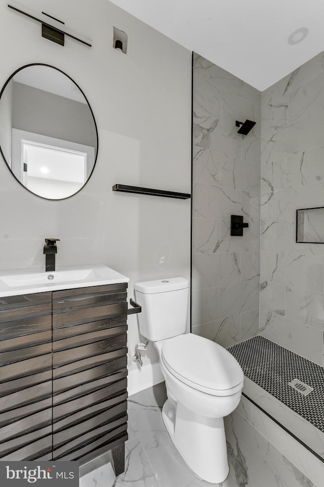 bathroom with a tile shower, vanity, and toilet