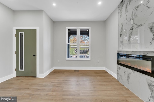 unfurnished dining area with a fireplace and light hardwood / wood-style flooring