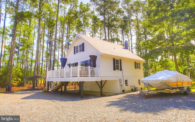 view of home's exterior with stairway, a chimney, a deck, and roof with shingles