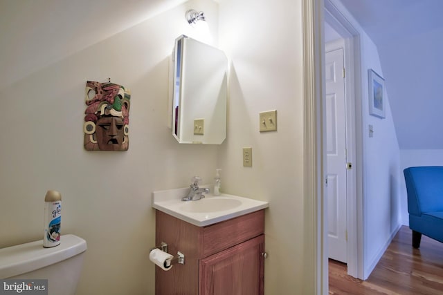 half bath with toilet, vanity, and wood finished floors