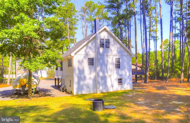 view of side of property featuring a lawn and a chimney
