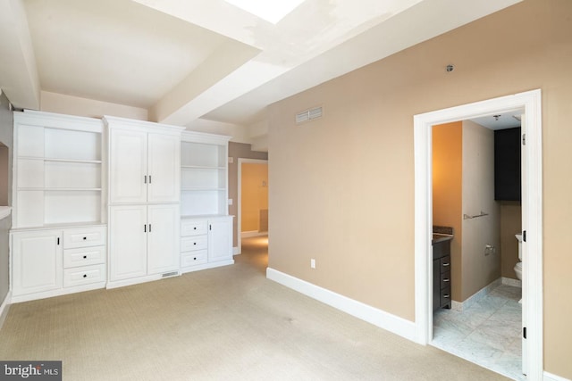 unfurnished bedroom featuring light colored carpet and connected bathroom