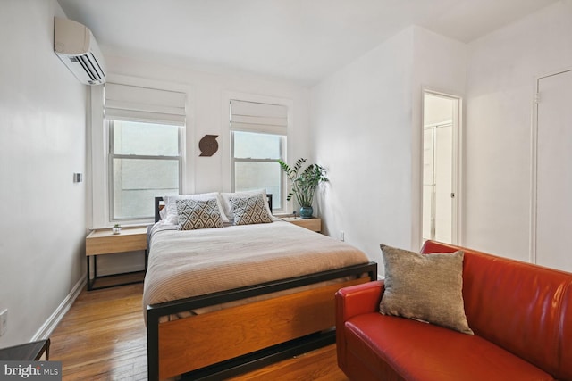 bedroom featuring hardwood / wood-style flooring and a wall unit AC