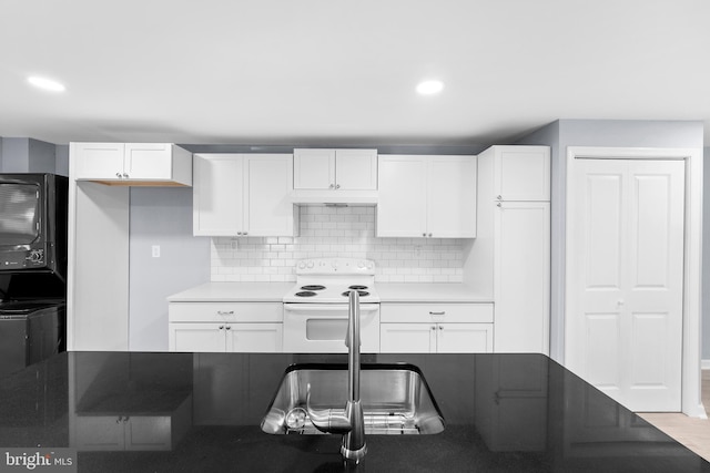 kitchen featuring backsplash, electric range, stacked washer / dryer, light wood-type flooring, and white cabinets