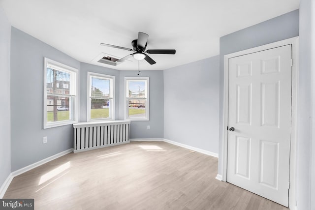 spare room featuring radiator heating unit, ceiling fan, and light hardwood / wood-style floors