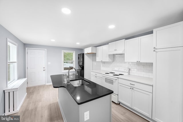 kitchen with white cabinets, light wood-type flooring, sink, white range with electric stovetop, and a center island with sink