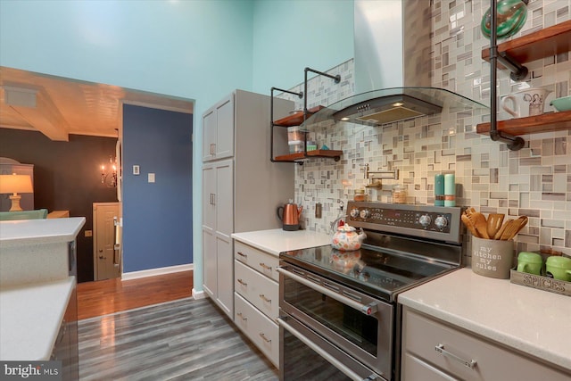 kitchen featuring hardwood / wood-style flooring, stainless steel electric stove, white cabinetry, wall chimney range hood, and beam ceiling