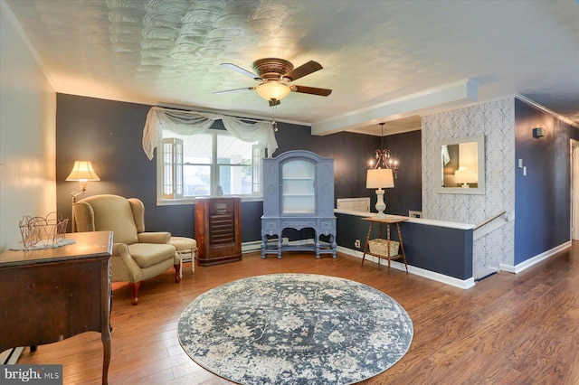 sitting room featuring ceiling fan, dark hardwood / wood-style floors, beamed ceiling, and ornamental molding