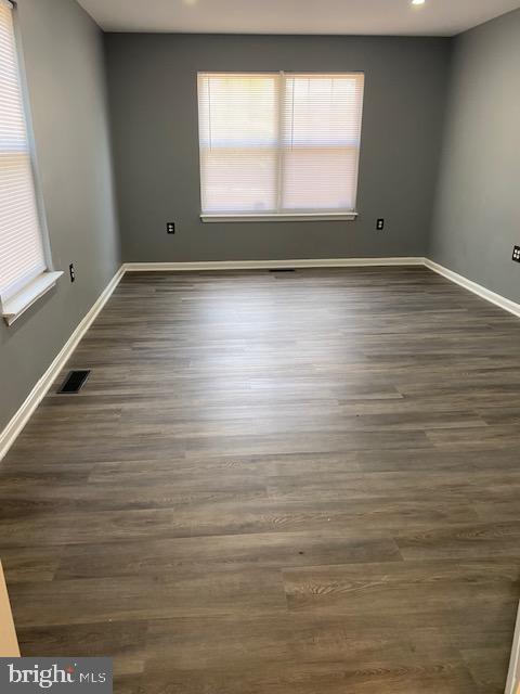 unfurnished room with dark wood-type flooring