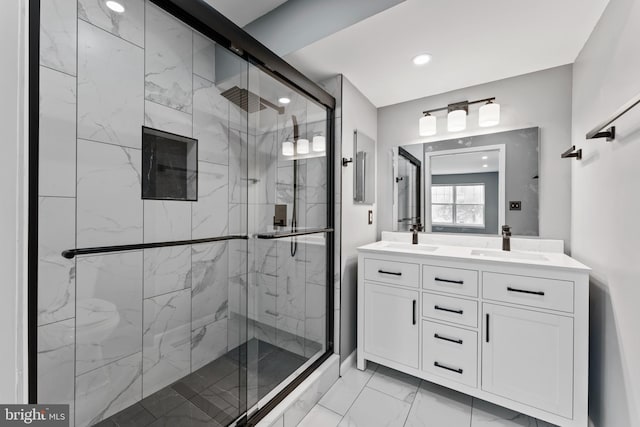 bathroom featuring a shower with door and vanity